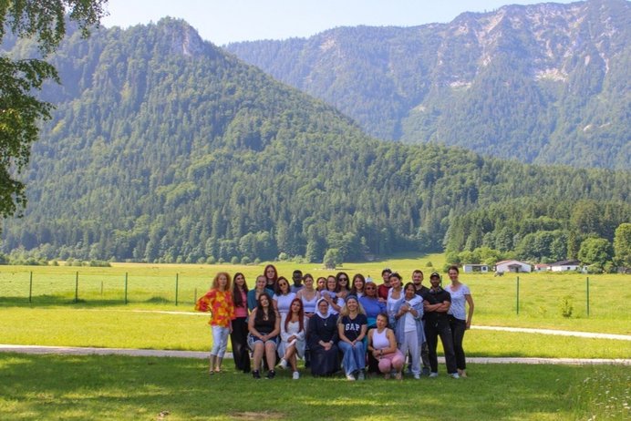 Gruppe von Schülerinne und Schülern mit Lehrern und einer Ordensschwester in Ordenstracht vor Bergpanorama